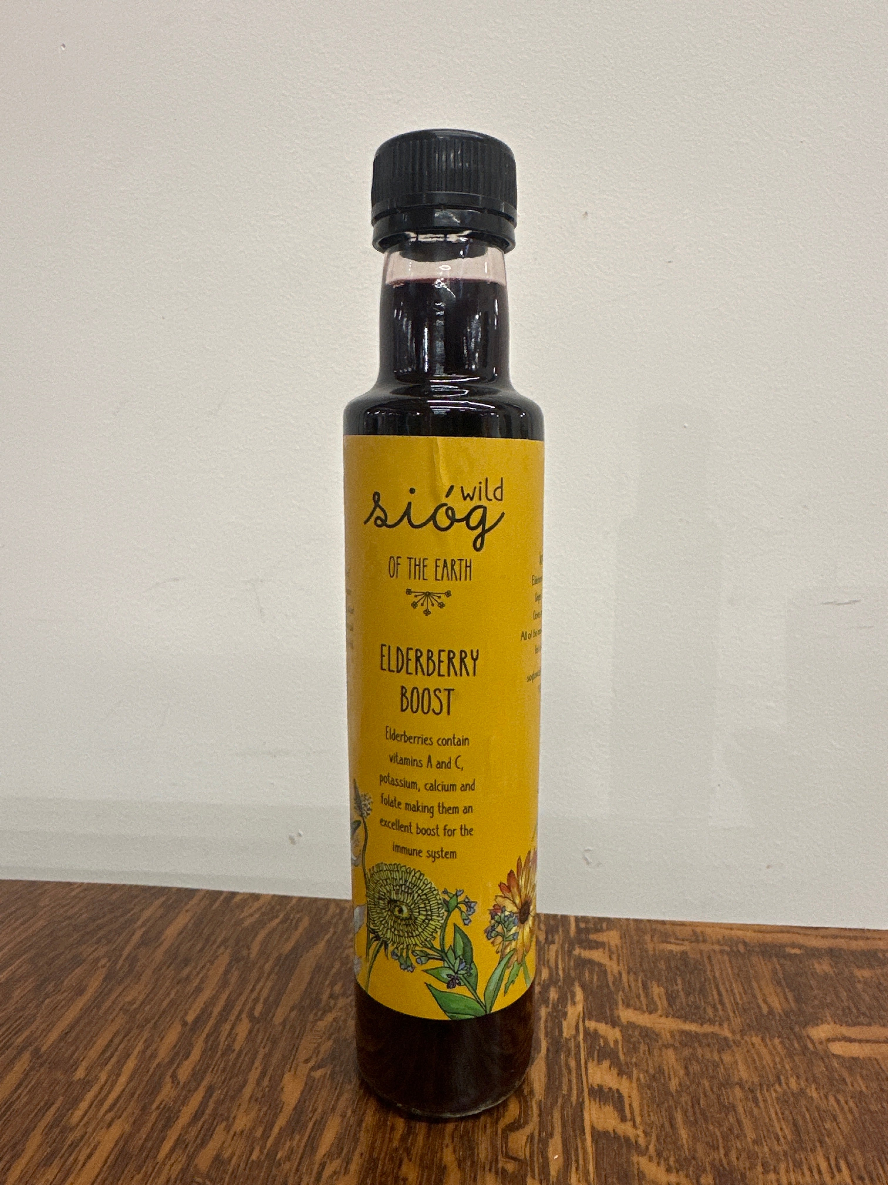 A bottle of Sióg of the Earth Elderberry Boost Tonic with a yellow label, containing 250ml of liquid.