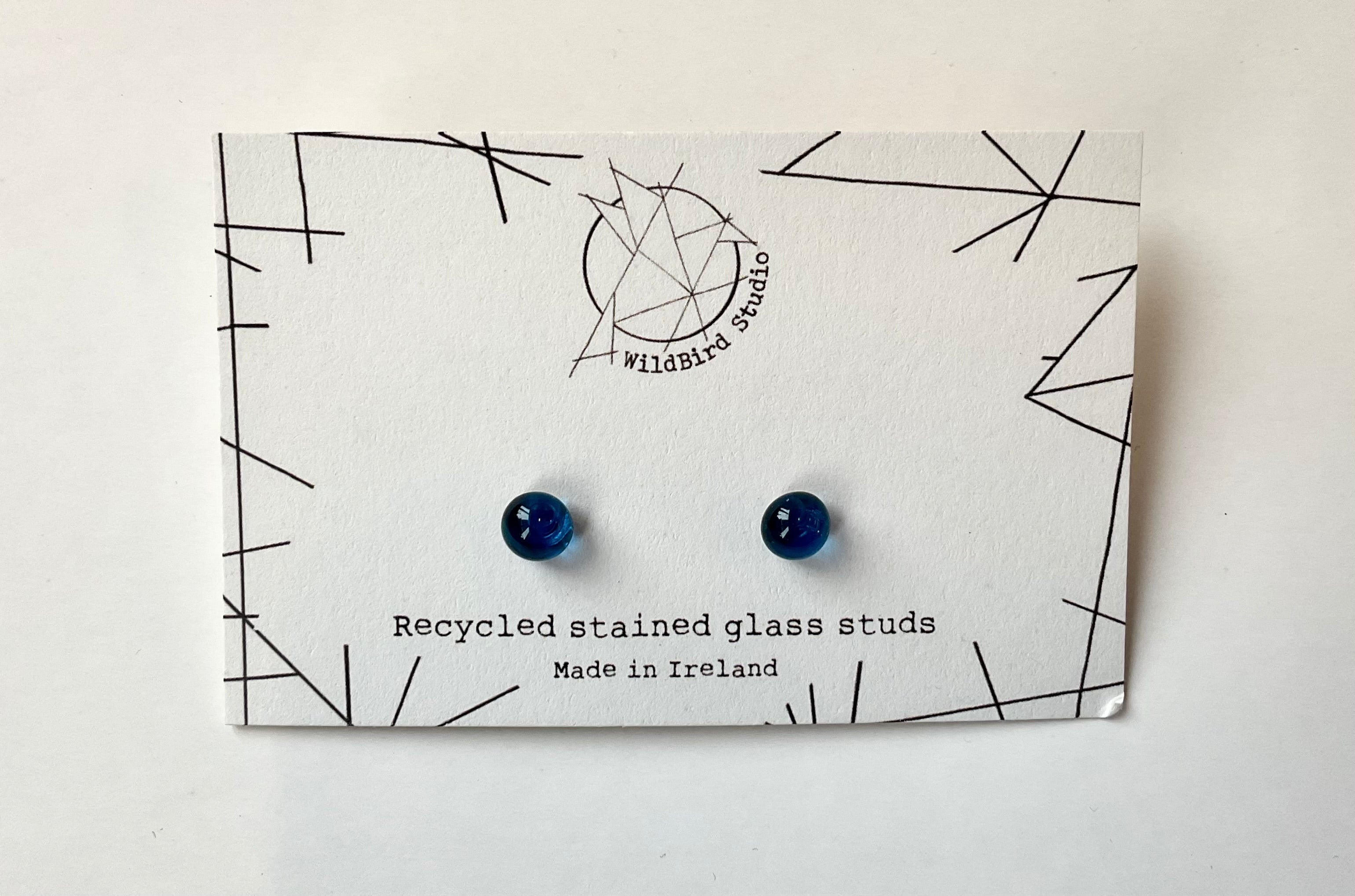 Pair of blue earrings on a WildBird Studio branded card with geometric design