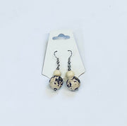 Pair of earrings with white and black amazon seed beads on a white card against a white background