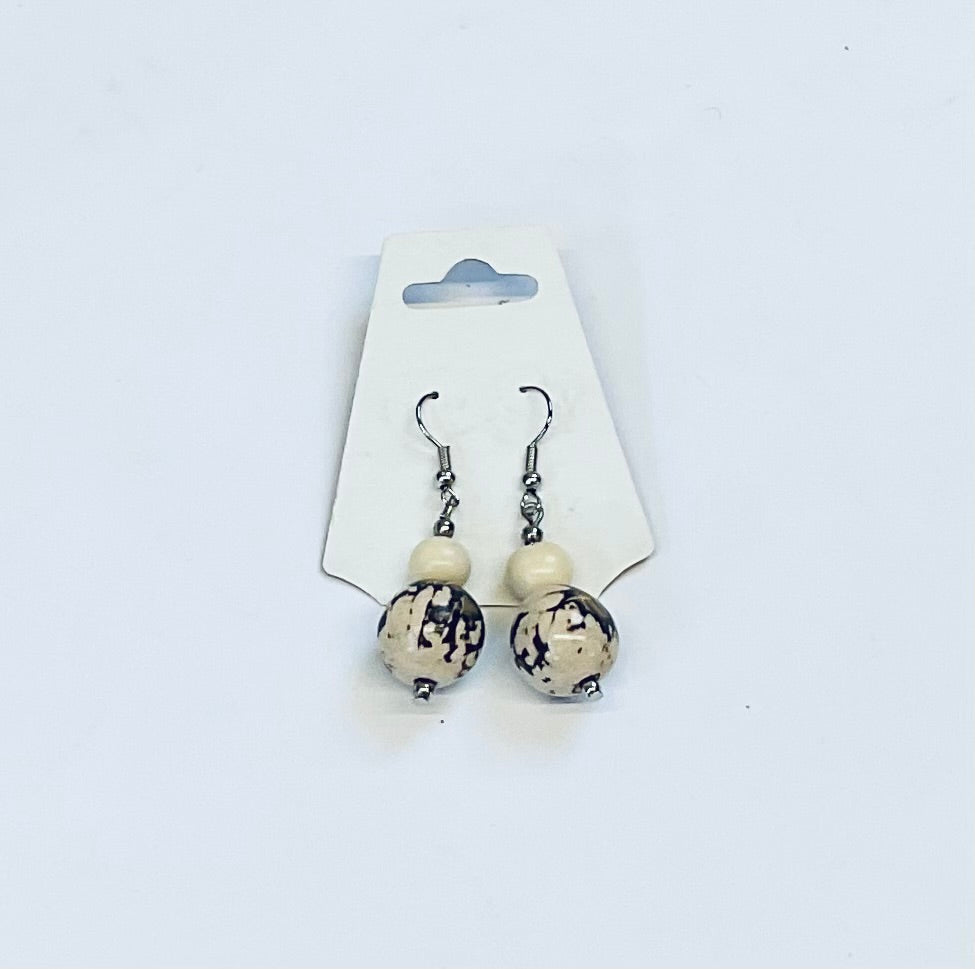 Pair of earrings with white and black amazon seed beads on a white card against a white background
