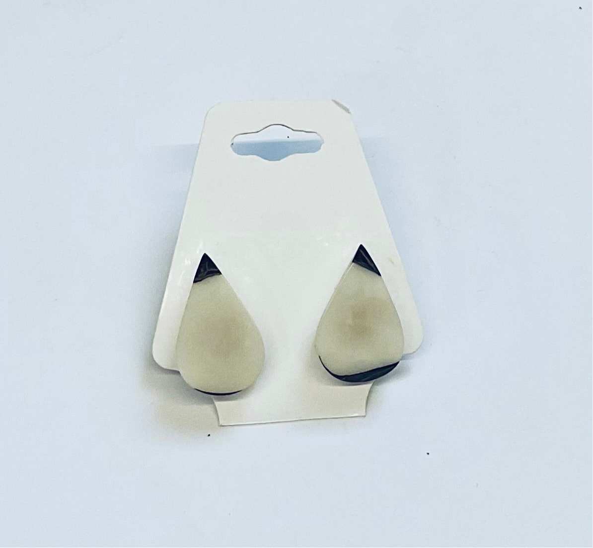 Pair of earrings on a white card against a light blue background