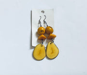 Pair of yellow fruit-shaped earrings on a white card against a light gray background