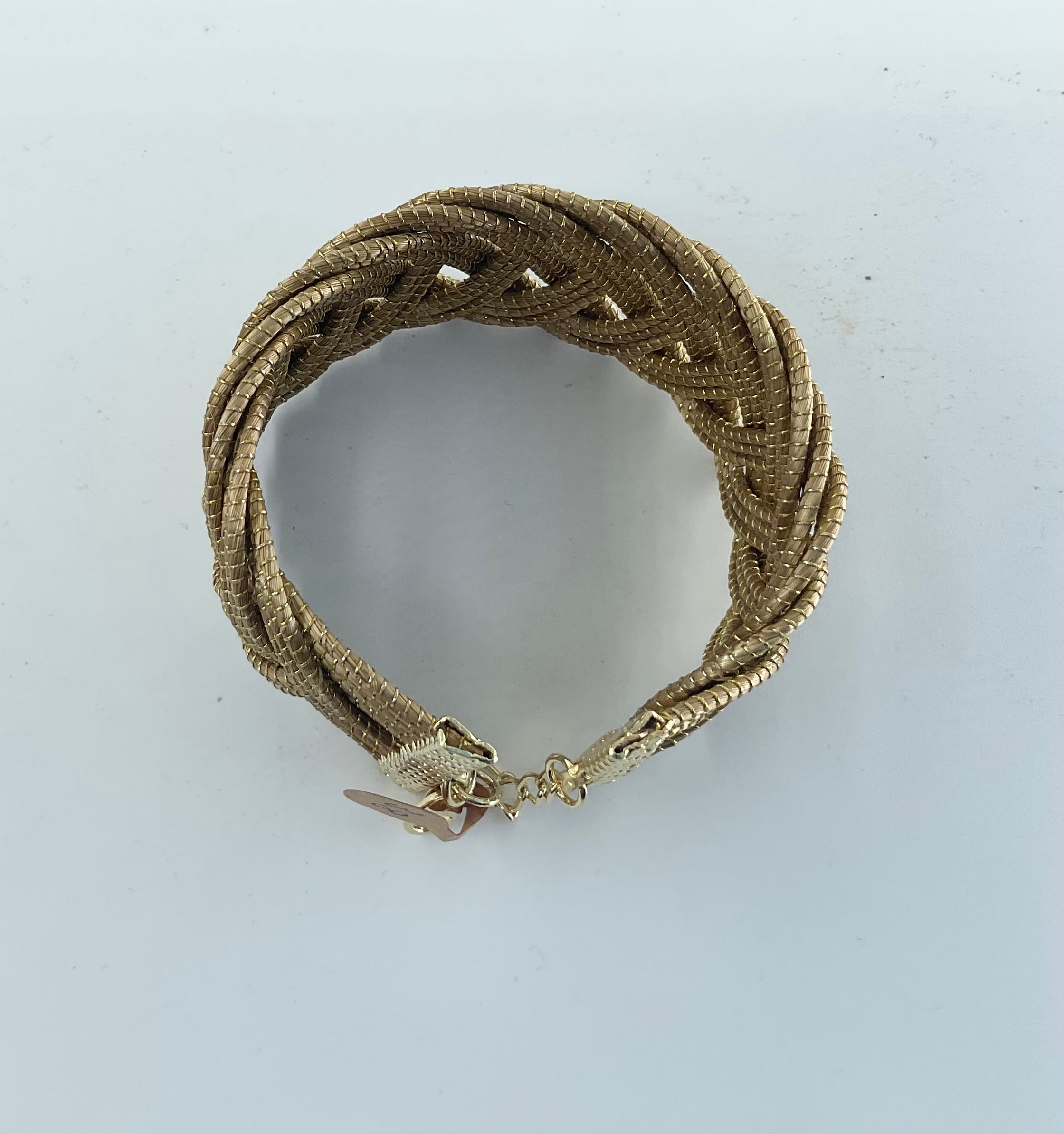 Gold braided bracelet on a light gray background
