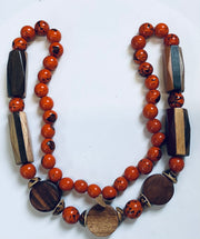 Necklace with orange beads and wooden accents on a white background
