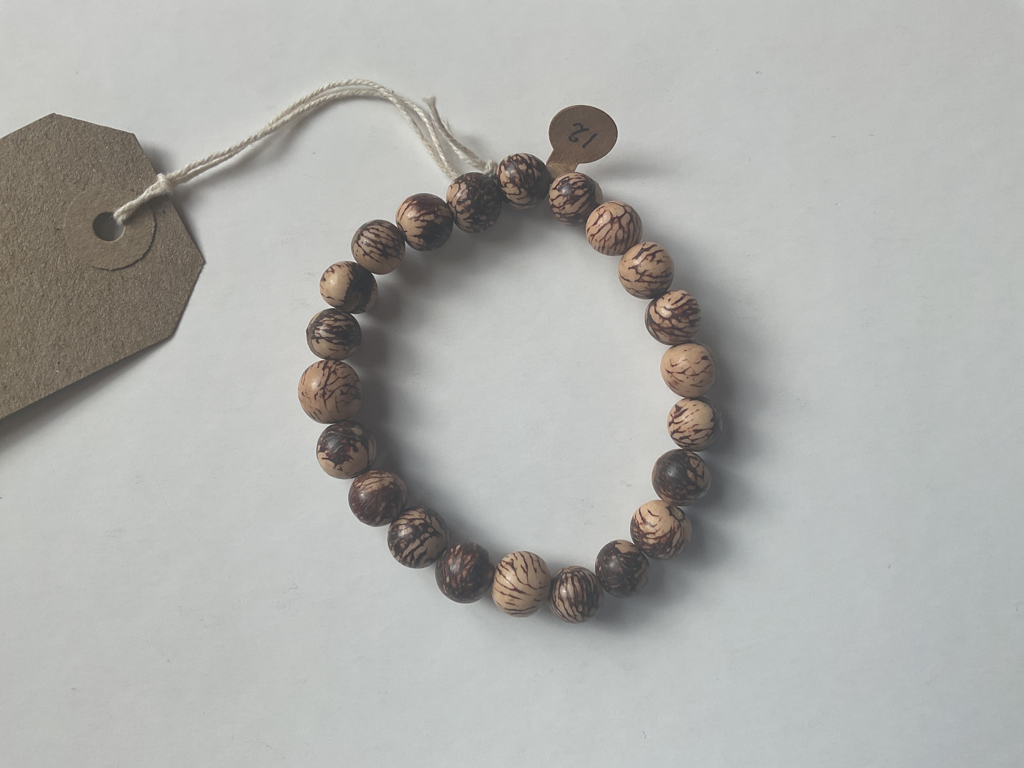 Wooden beaded bracelet with a tag on a light gray background