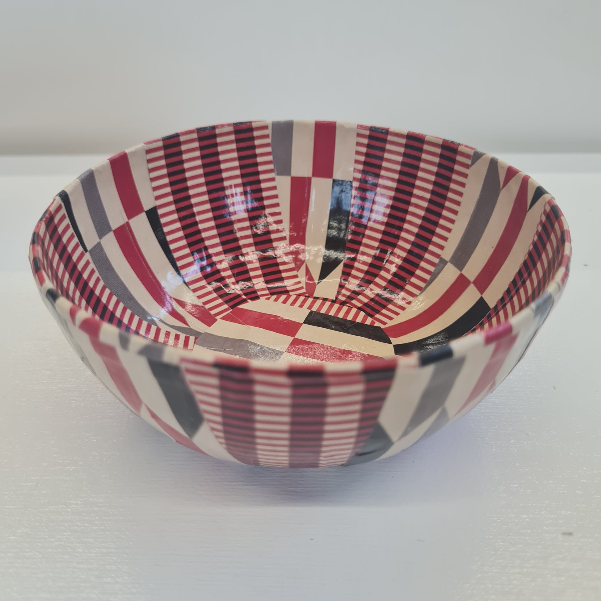 A paper mache bowl with a red and black striped pattern.