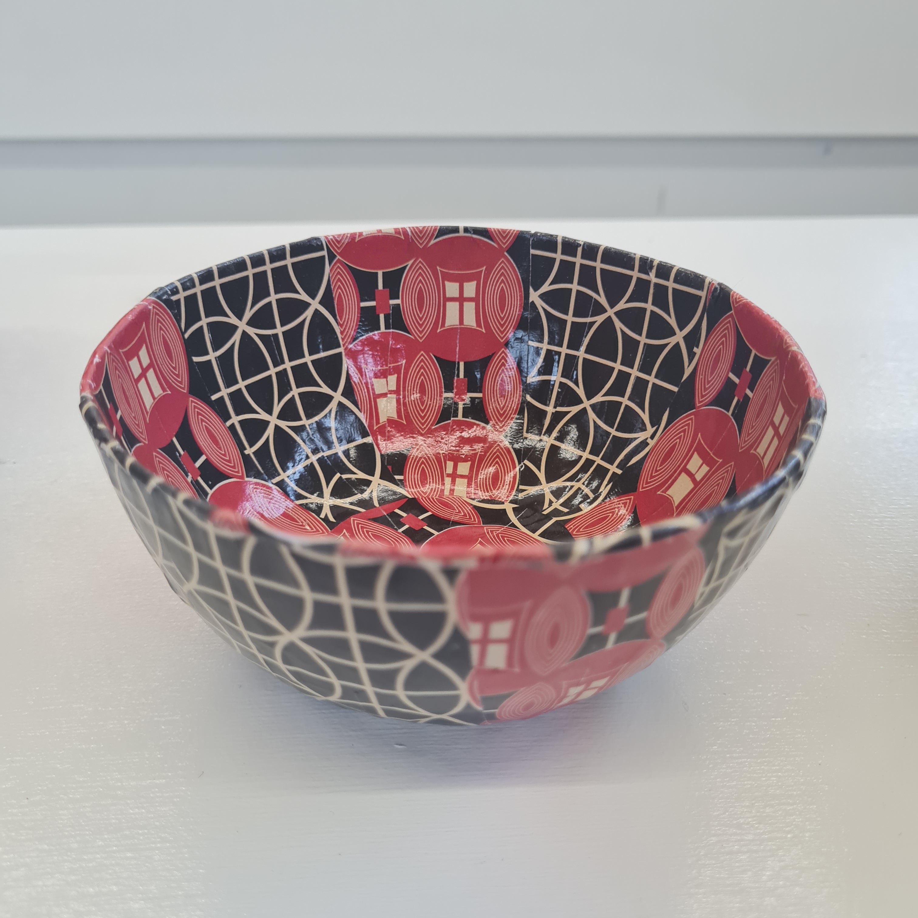 a paper mache bowl with black, red and white patterns