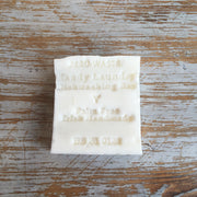 A white bar of laundry or dishwashing soap with 'Palm Free' and 'Irish Handmade' printed on it, placed on a wooden surface.