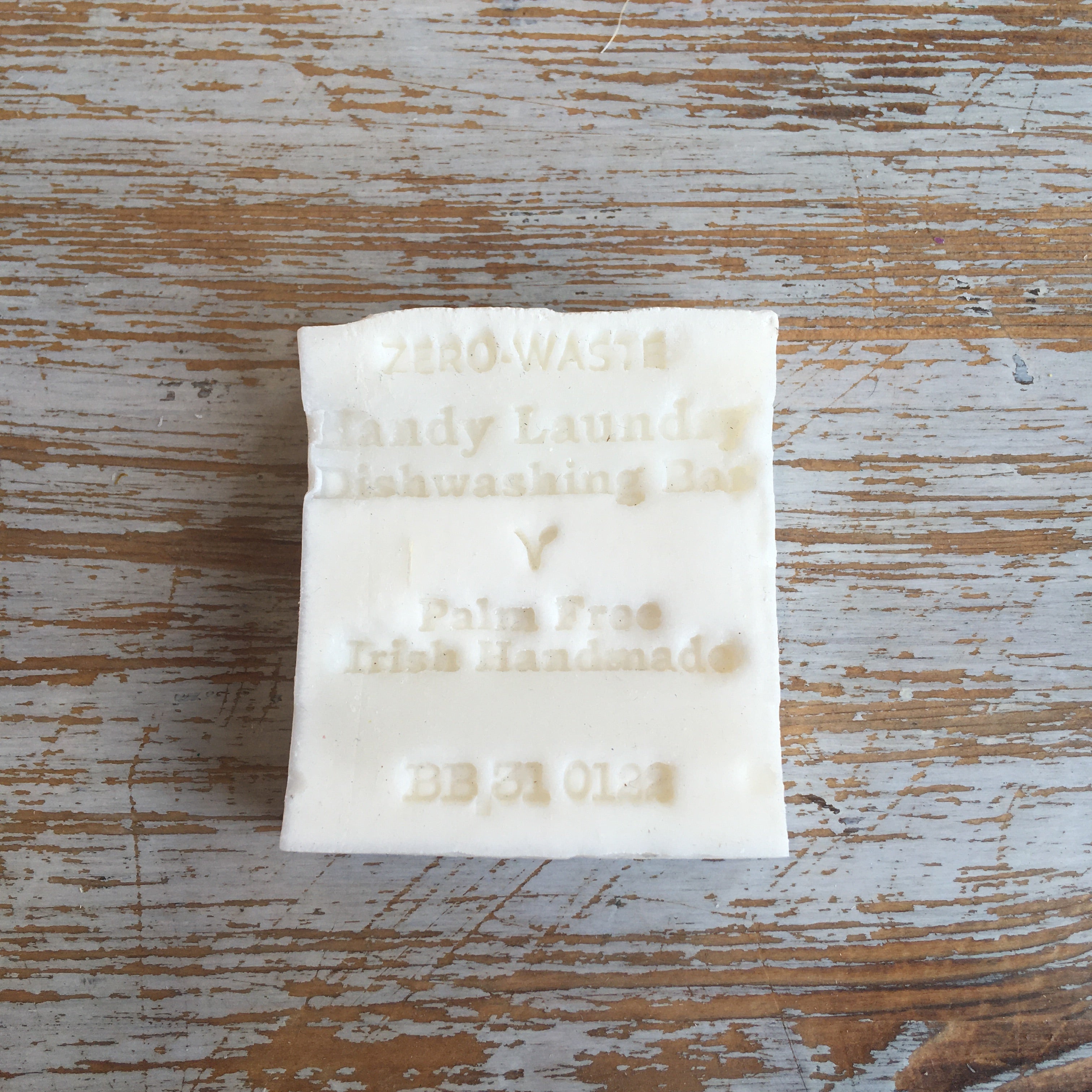 A white bar of laundry or dishwashing soap with 'Palm Free' and 'Irish Handmade' printed on it, placed on a wooden surface.