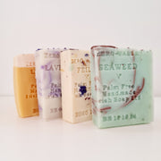 A selection of handmade soap bars displayed side by side, with varying colors and designs, including 'Palm Free' text on each wrapper.