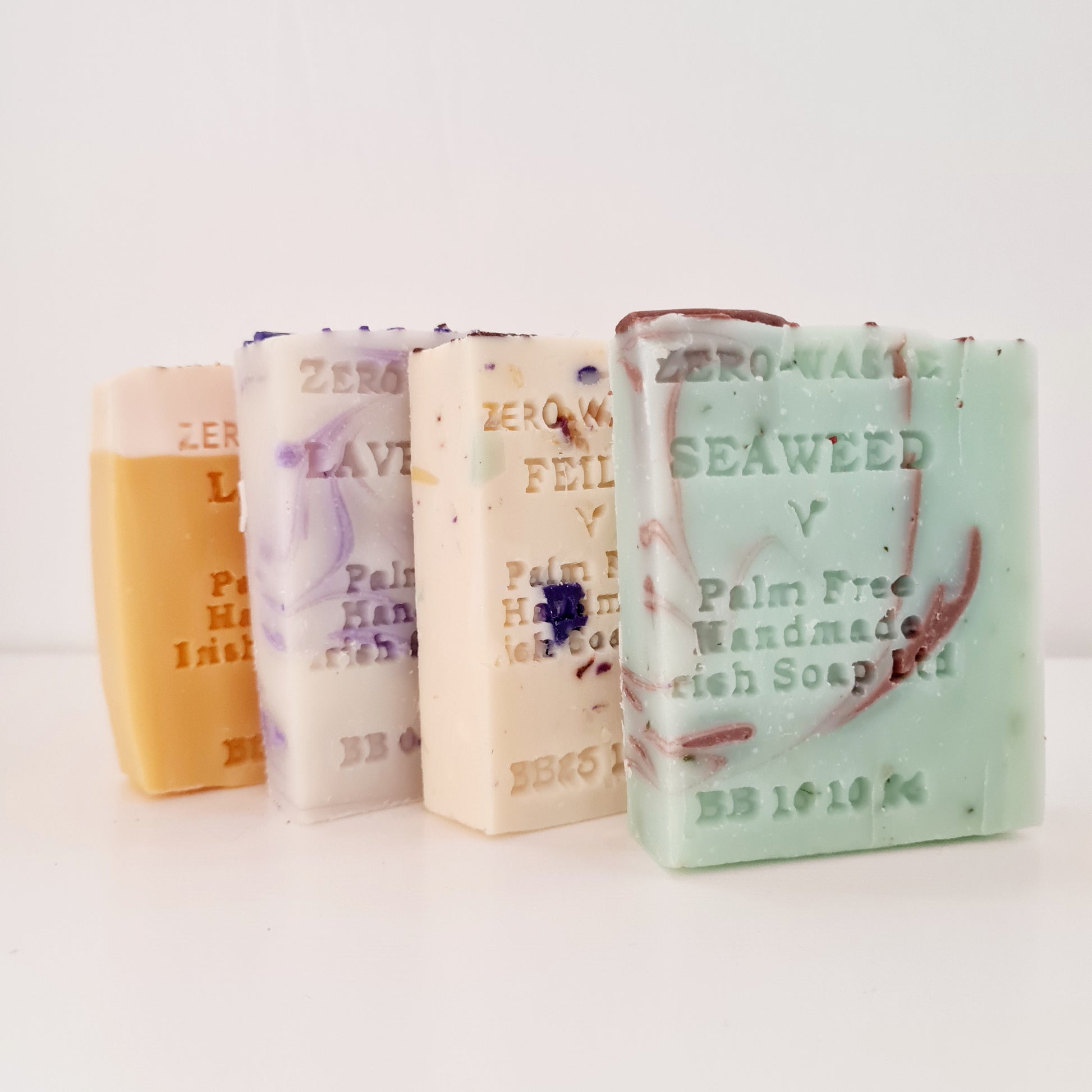 A selection of handmade soap bars displayed side by side, with varying colors and designs, including 'Palm Free' text on each wrapper.